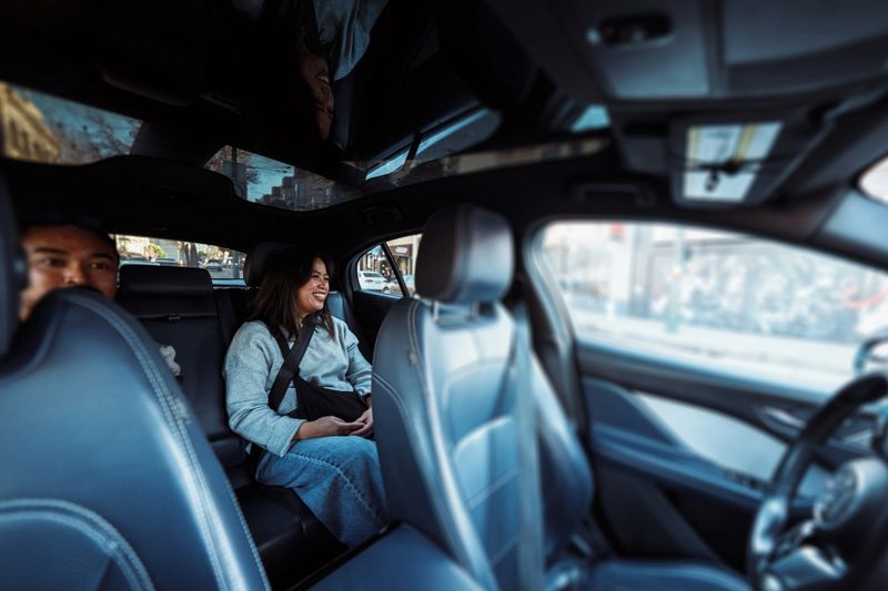 View shot from the front passenger seat of a vehicle showing a Filipino couple in their 30s riding in the back seat of an autonomous driverless taxi in San Francisco, California, USA.