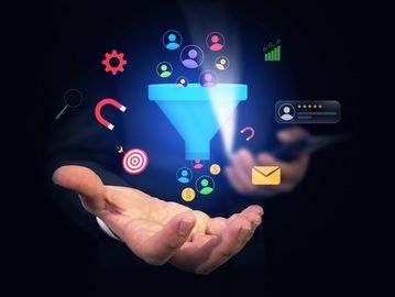 Digital marketing funnel with various icons floating above a person's outstretched hand.