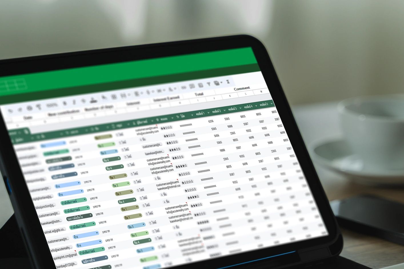 Person working on a tablet displaying a colorful spreadsheet with data and ratings.