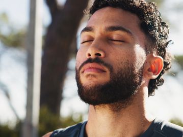 Man with closed eyes enjoying sunlight outdoors.
