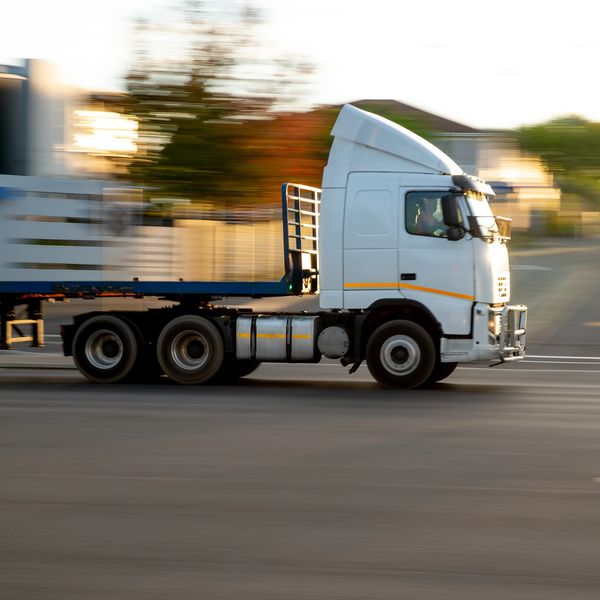 White semi-truck speeding on a road.