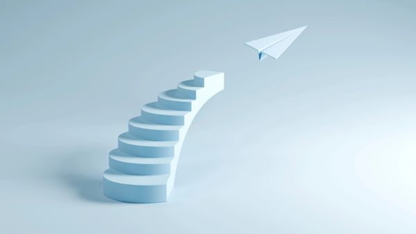 Curved stairs leading to a flying paper airplane.