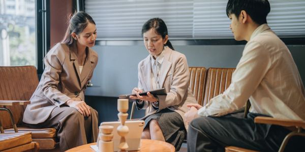 Three professionals discussing work around a table in an office.