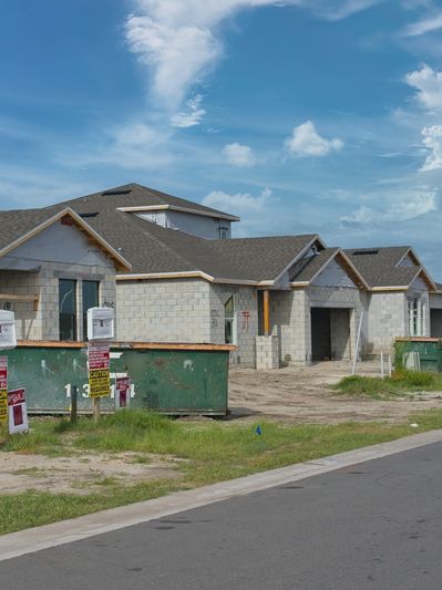 New houses under construction with dumpsters and caution signs.