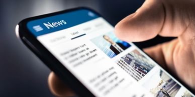 Person scrolling news on smartphone.