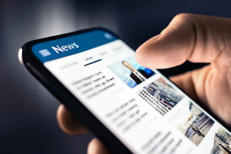 News and press release. Headlines and newspaper media in phone. Reading articles online. Mobile in hand. Feed, breaking report, or business publication. Latest daily journalism.