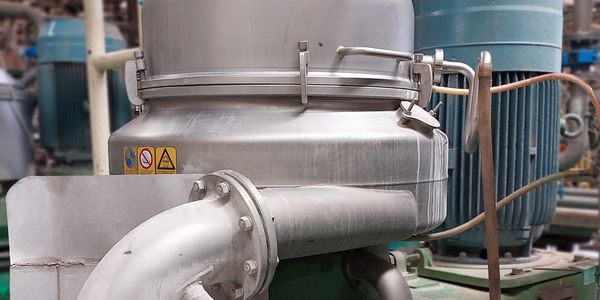 Close-up of industrial stainless steel machinery with pipes and electric motor.