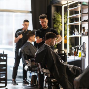 Barbers cutting men's hair in a modern barbershop.