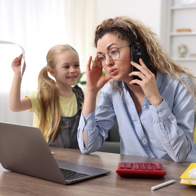 An image showing a young parent with a child who is trying to distract her whilst she is working.
