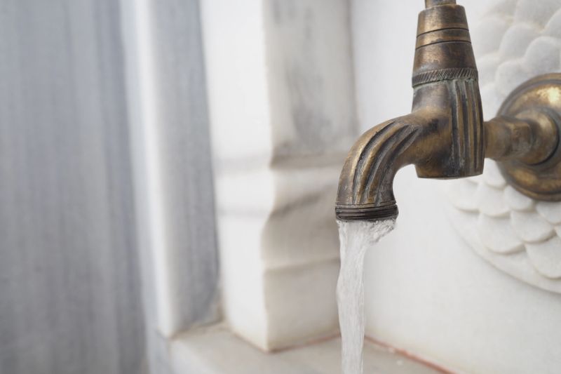 A stunningly beautiful brass faucet elegantly pouring water, placed against luxurious marble decor