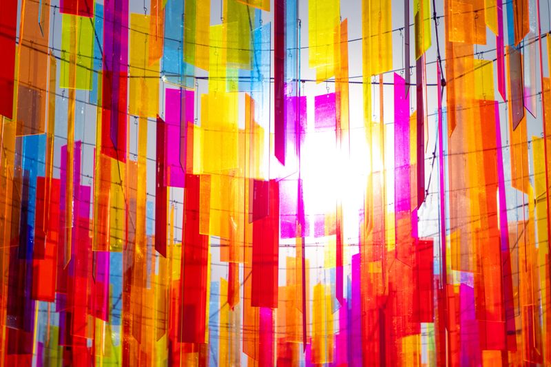 The sun shines through a warm arrangement of colorful glass hanging by wires.