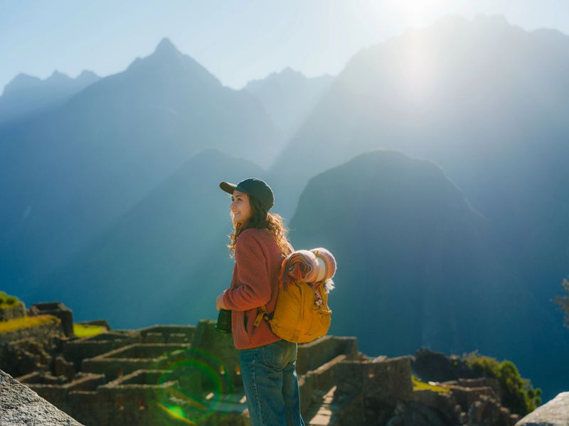 Serene woman with backpack  looking at scenic view of Machu Picchu in Peru