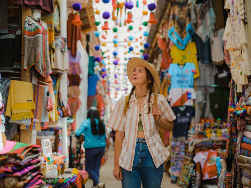Woman choosing souvenirs on Pisac Market during experiential trip to Sacred Valley, Peru