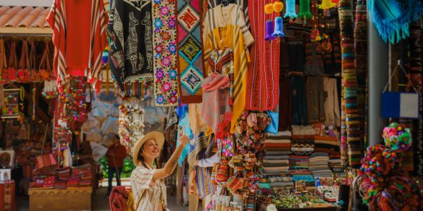 Mujer comprando en un mercado de artesanías colorido.