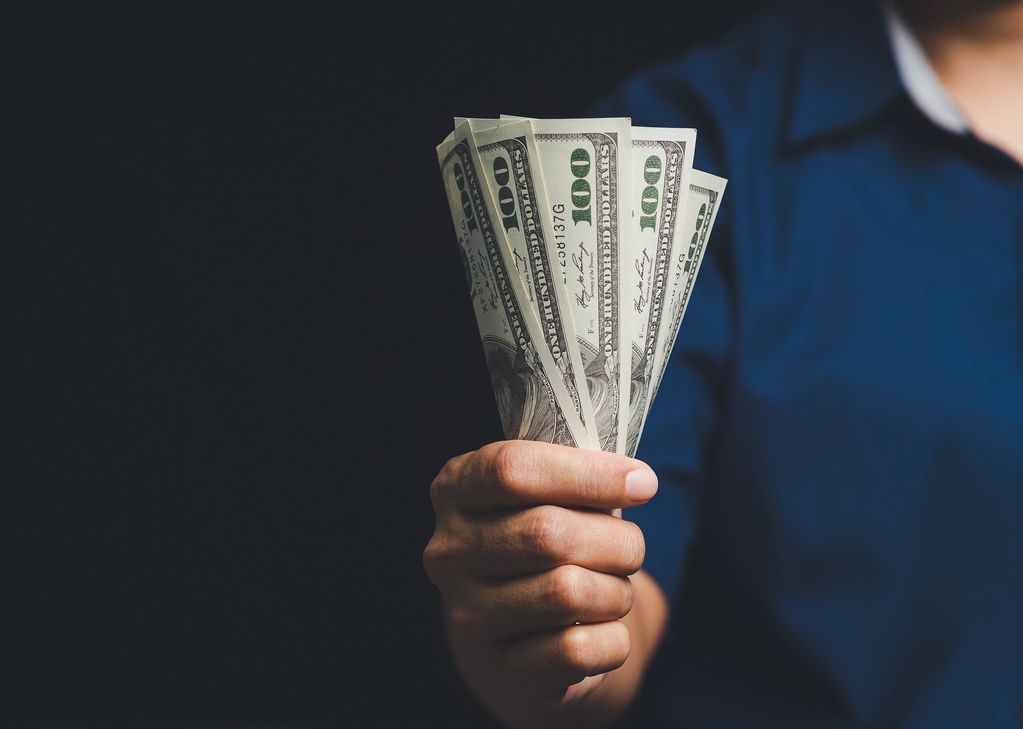 Hand holding several 100-dollar bills.