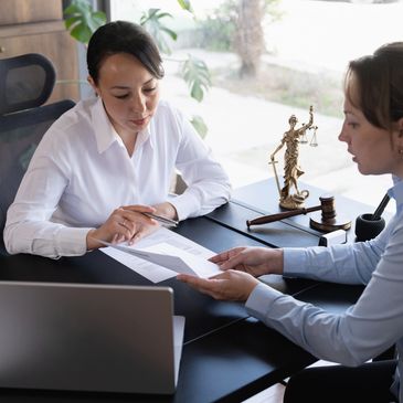 Dos mujeres discutiendo documentos legales en una oficina.