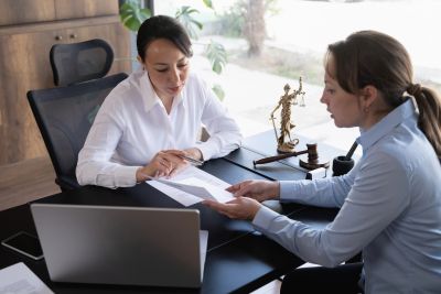 Two women discussing legal documents in an office.