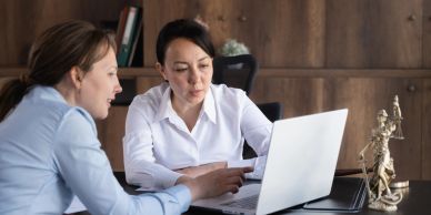 Two women discussing something on a laptop.