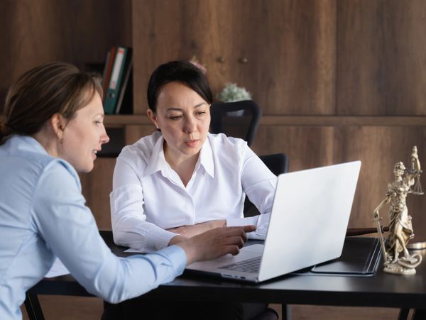 Two women discussing something on a laptop in an office.