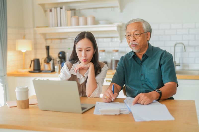 asian family home finance attractive young woman assisting her elderly father with her finances at home woman sitting and explaining financial documents to her dad in their home