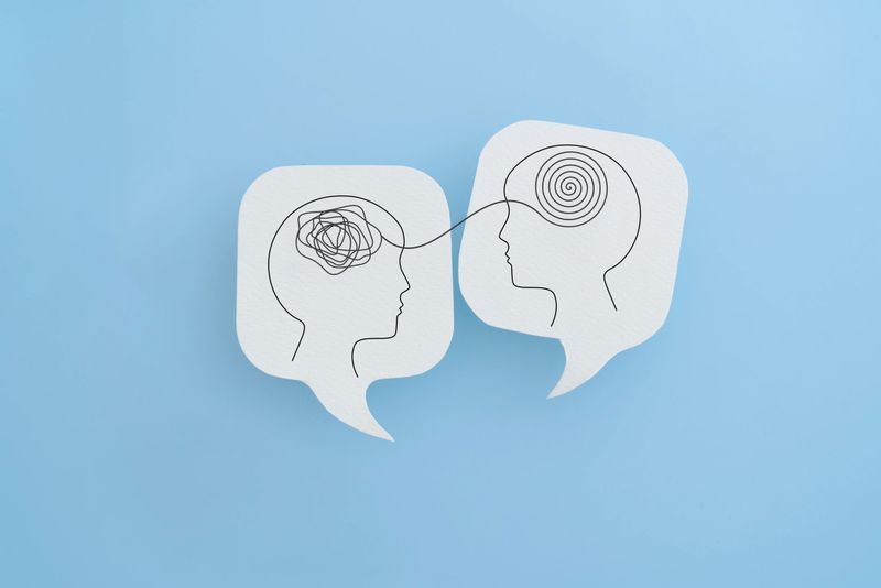 Mental health, brain disorder, World mental health day, Alzheimer, Psychology concept. Human head with Tangle of thoughts and clear line on real white speech bubble paper cut with blue background