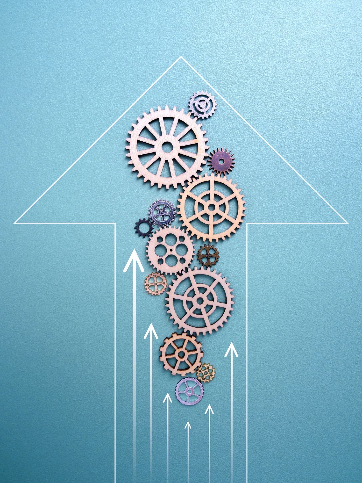 Wooden gears arranged inside an upward arrow on a blue background.