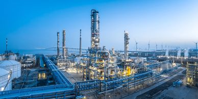 A large industrial refinery complex under a clear blue sky at dusk.