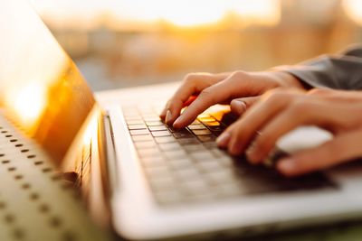 Hands typing at a laptop as they search for CPD-certified online learning through Optimum Training a