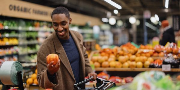 Man happily choosing apples in grocery store.