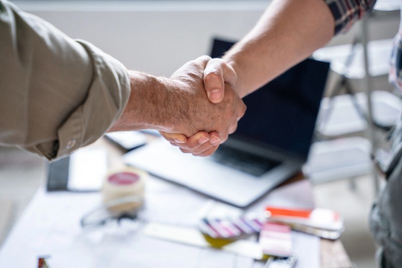 Close-up of handshake of two individuals at a construction site. Conclusion agreement of a house renovation.