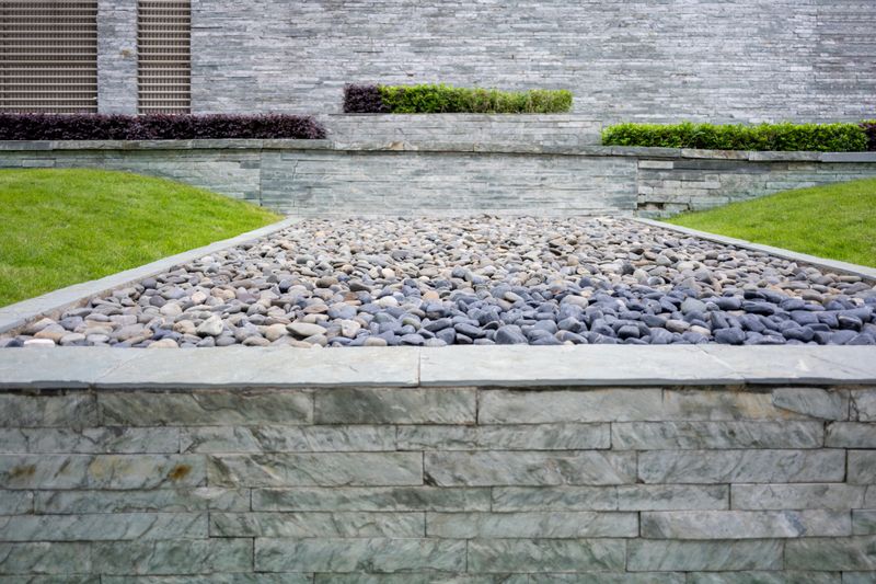 A contemporary garden design featuring a stone pathway surrounded by lush green grass and neatly arranged plants, creating a serene outdoor space suitable for relaxation or as an architectural feature.
