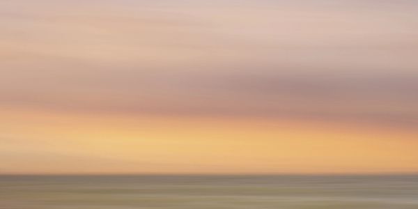 Blurry seascape with soft pastel sunset hues.