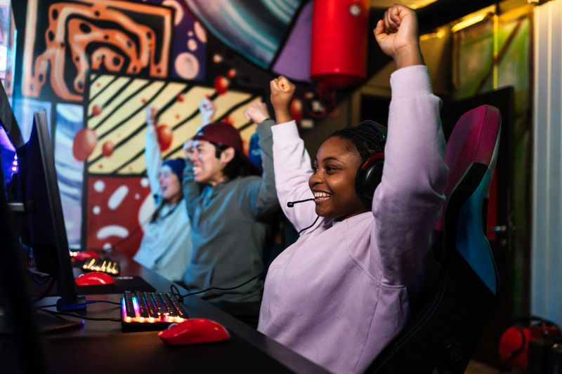 Group of diverse gamers celebrating their hard-fought victory after triumphing in an online tournament, filled with excitement and joy
