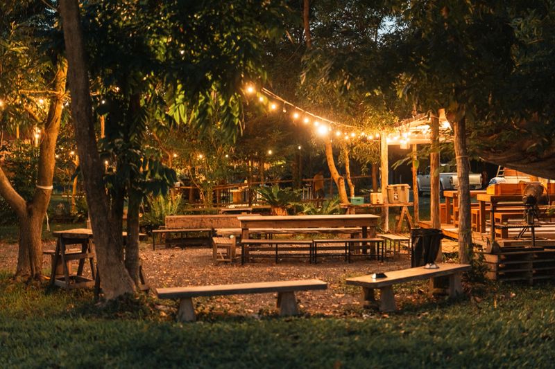 cozy outdoor dining area set up for a rustic BBQ party offering relaxed camp style atmosphere where friends, families gather to enjoy grilled food and create unforgettable memories under the lights