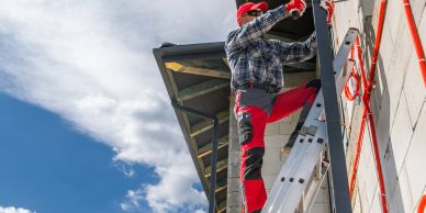 Worker climbing a ladder on a building under construction.