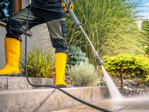Person pressure washing outdoor stone steps.