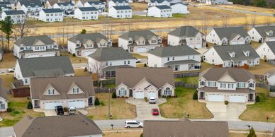 Aerial view of a suburban neighborhood with houses and cars on driveways.