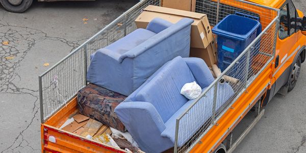 Orange truck loaded with blue couches, boxes, and a blue bin.