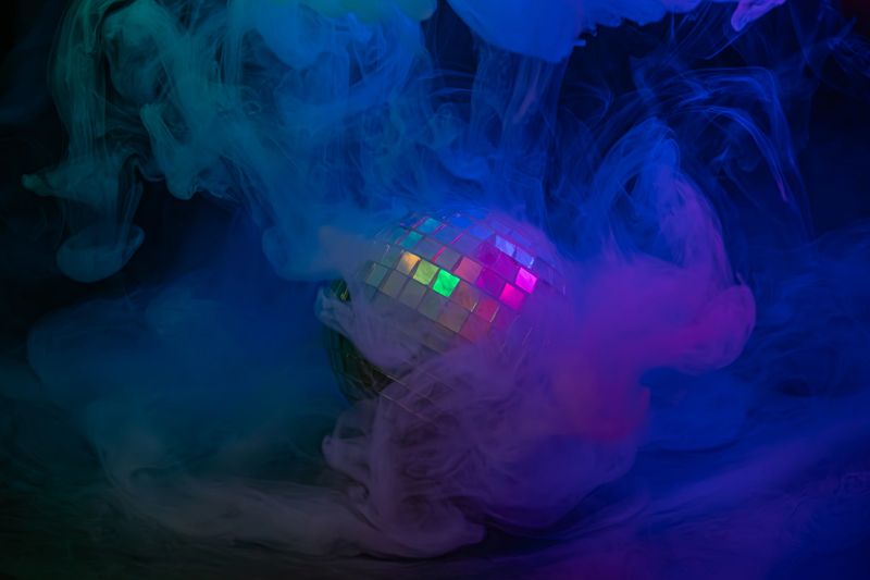 Image portrays a lively nightclub ambiance with a colorful disco ball and blue smoke, ideal for marketing nightlife, events, or entertainment venues