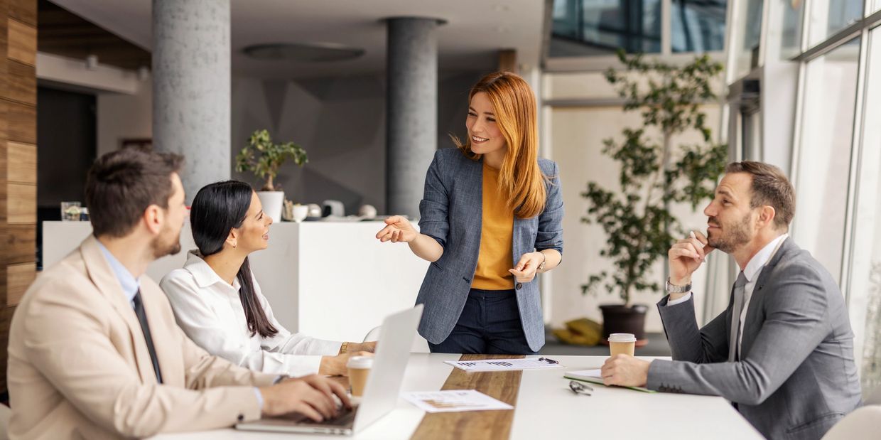 Businesswoman leading a meeting with colleagues in an office.