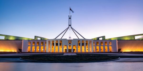 Parliament House in Canberra at dusk with lights on.