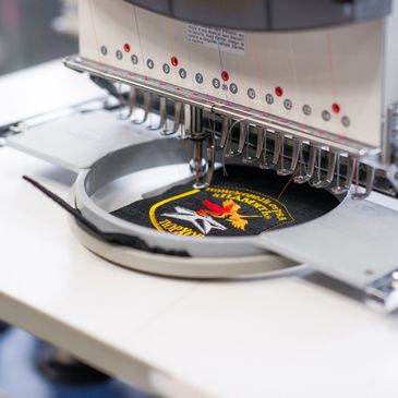 Close-up of an embroidery machine stitching a colorful patch.