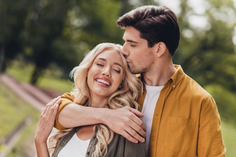 Portrait of beautiful handsome adorable couple kissing cuddling enjoying idyllic pastime honey moon outdoors.