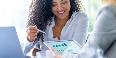 Businesswoman reviewing charts on a tablet with a colleague.