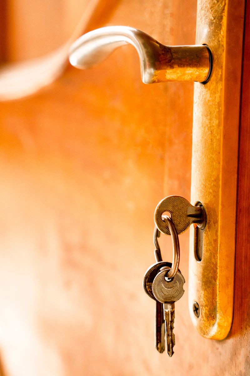 A close-up shot of a key hanging in a door lock, with the door displaying a rich golden brown tone. The image captures the detailed texture and color of the wooden door, highlighting the key as it dangles in place, symbolizing security and home entrance.