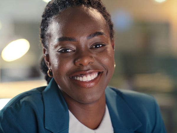 Smiling professional woman in a teal blazer, radiating confidence and warmth.