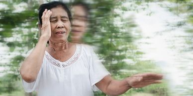 Elderly woman experiencing dizziness with blurred motion effect.