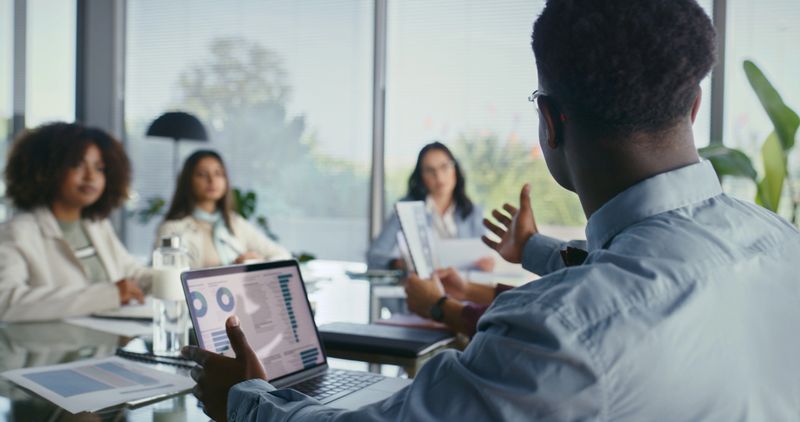 Meeting, data and people in office with laptop, discussion and graphs for sustainable business strategy. Team, planning and CSR consultant in conference room with ESG statistics for risk management