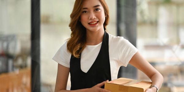 Smiling woman holding a package indoors.