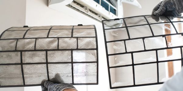 Dirty and clean air conditioner filters being compared.